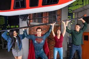 Tourists interacting with Superman wax figure at Madame Tussauds.