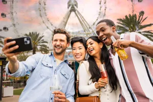 Four adults taking a selfie with thier drinks in front of The Orlando Eye