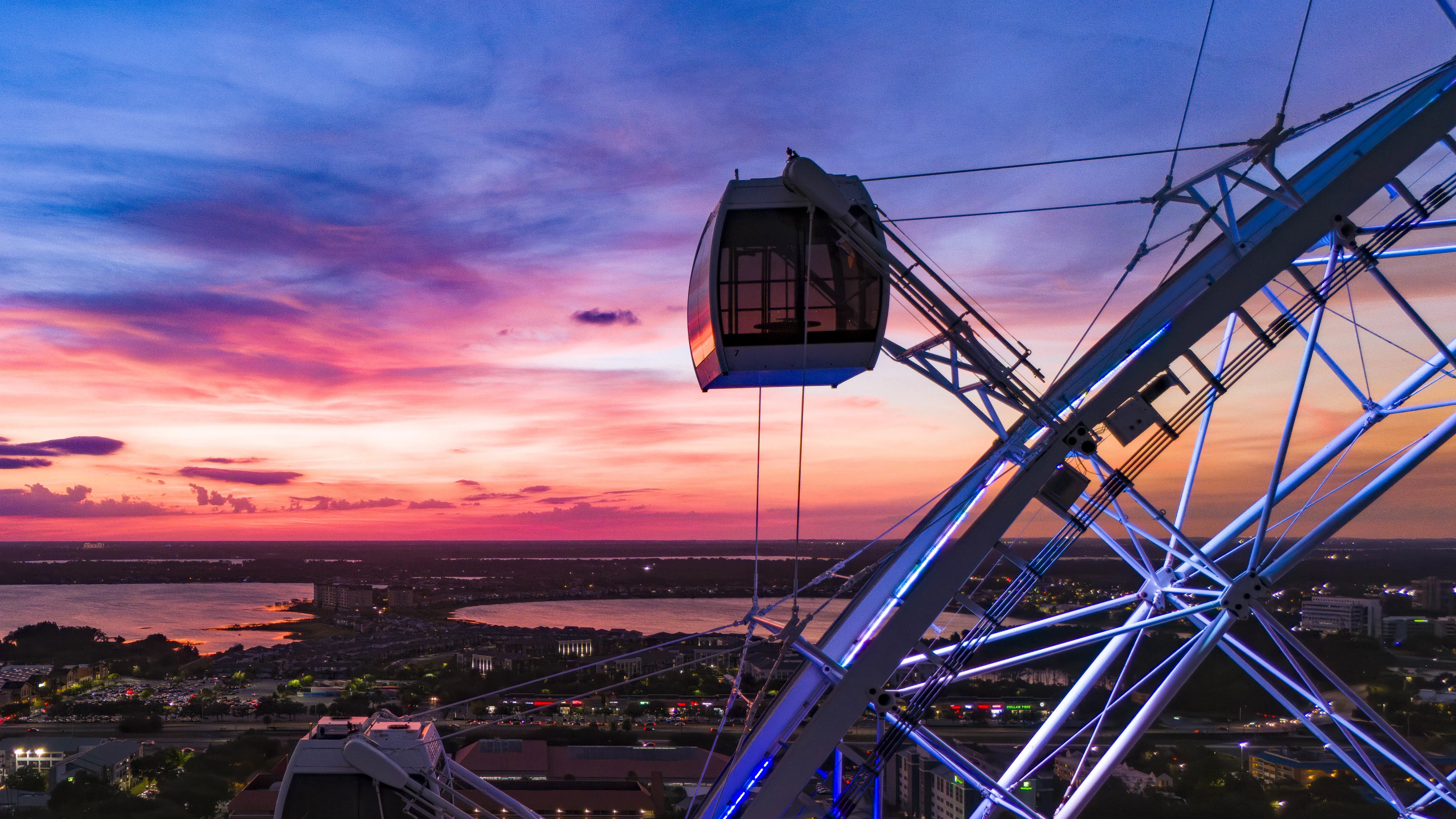 Drone view of a singular capsule of The Orlando Eye during dusk. International Drive and Sand Lake are in the background.
